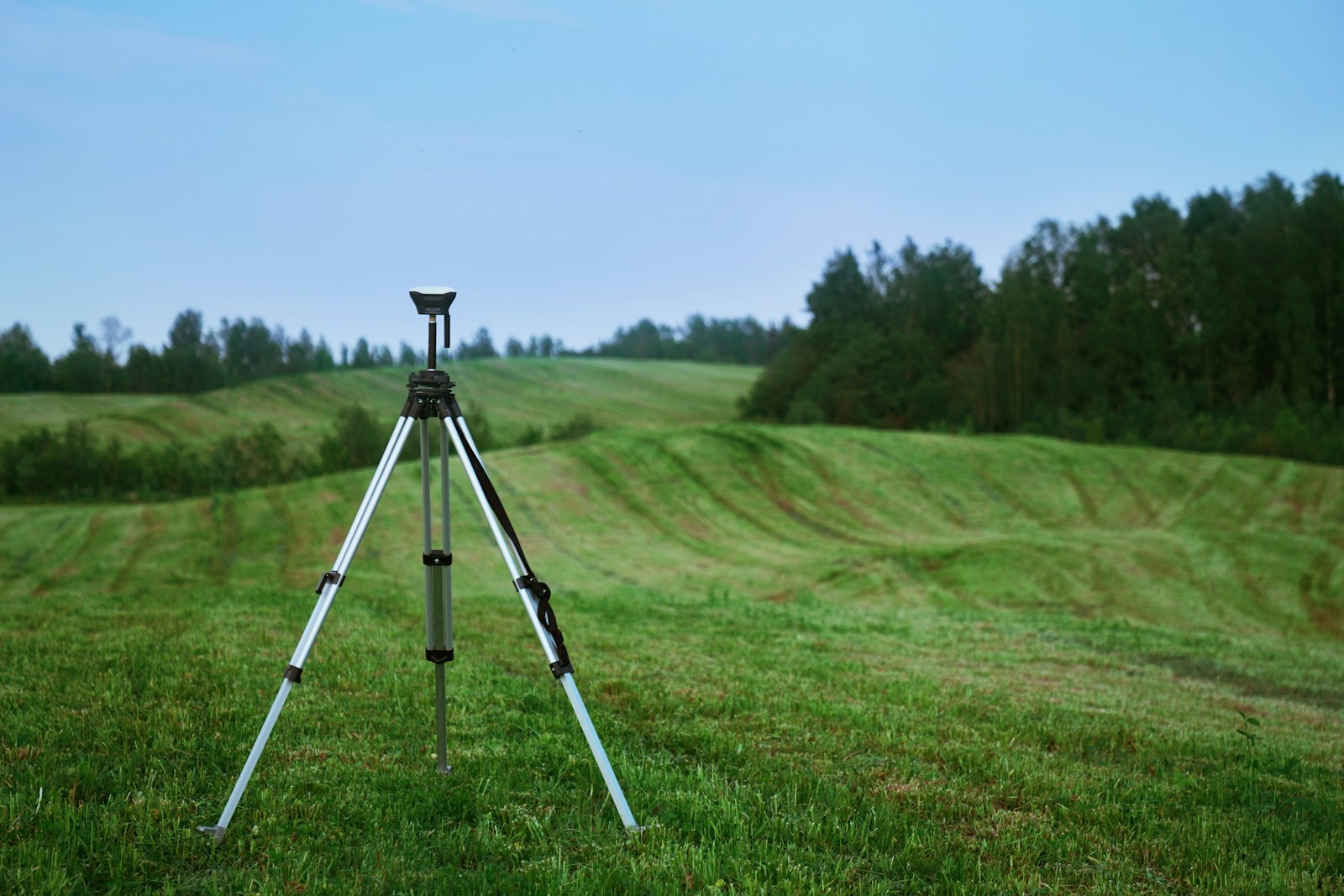 GNSS survey receiver operating on a tripod in an open field